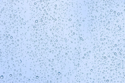 Full frame shot of wet glass against blue sky
