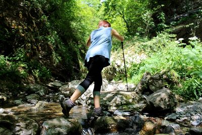 Rear view of woman walking on rocks in forest