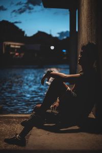 Side view of young woman smoking at night