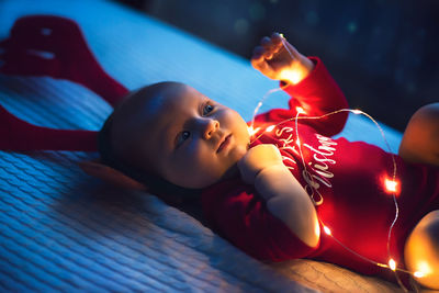 Cute baby by illuminated lights at home