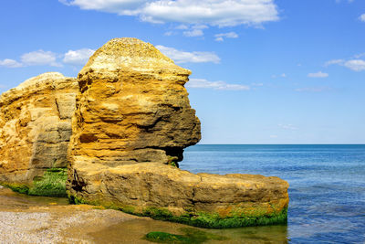 Rock formation by sea against sky