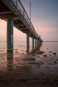Low angle view of bridge over sea against sky during sunset