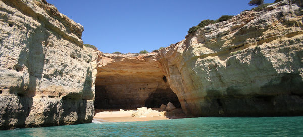 Rock formations by sea against clear sky