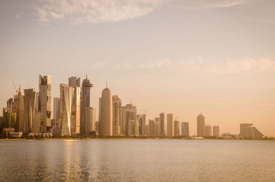 Sea by modern buildings against sky in city