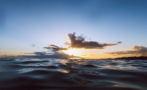 Surface level of sea against sunset sky
