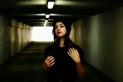 Portrait of young woman standing by wall