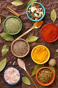 High angle view of spices in colorful bowls on paper