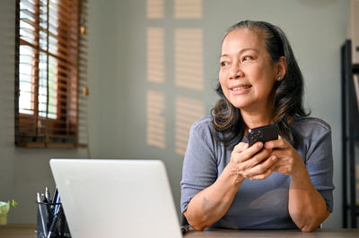 Young woman using mobile phone while sitting at home