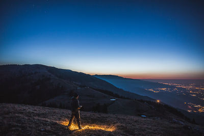 Man standing on mountain road against sky at night