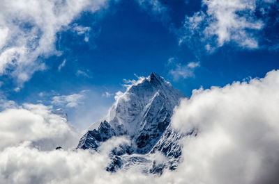 Clouds at snow covered mountain peak