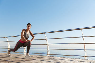 Portrait of smiling young woman exercising on bridge