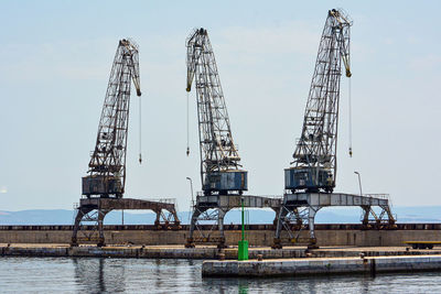 Cranes at pier against sky