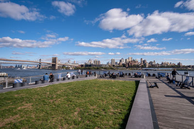 View of buildings by river against cloudy sky