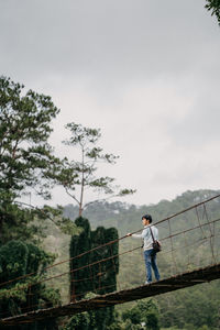 Man standing by railing against sky