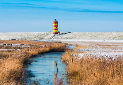 Lighthouse by sea against sky