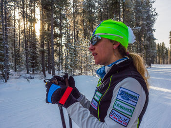 Side view of young woman in snow covered forest