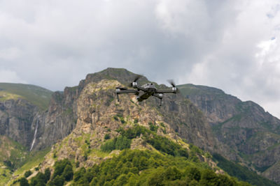 Drone with camera flying over mountain fields.