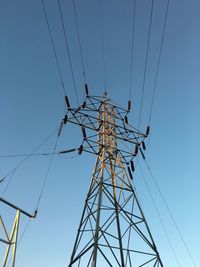 Low angle view of electricity pylon against clear sky