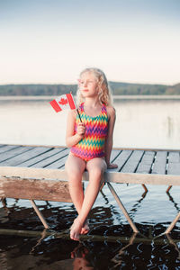 Full length of woman sitting by lake