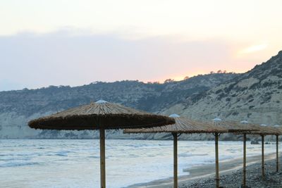 Gazebo on beach by mountains against sky