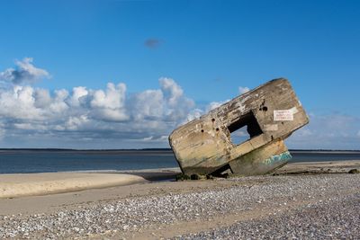 Abandoned boat on beach against sky