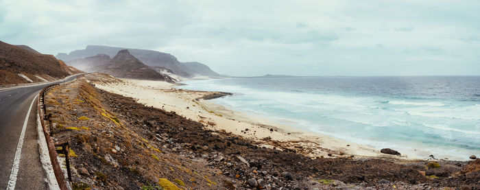 Scenic view of road by beach against sky