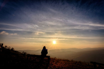 Rear view of man on field against sky during sunset