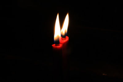 Close-up of lit candle in darkroom