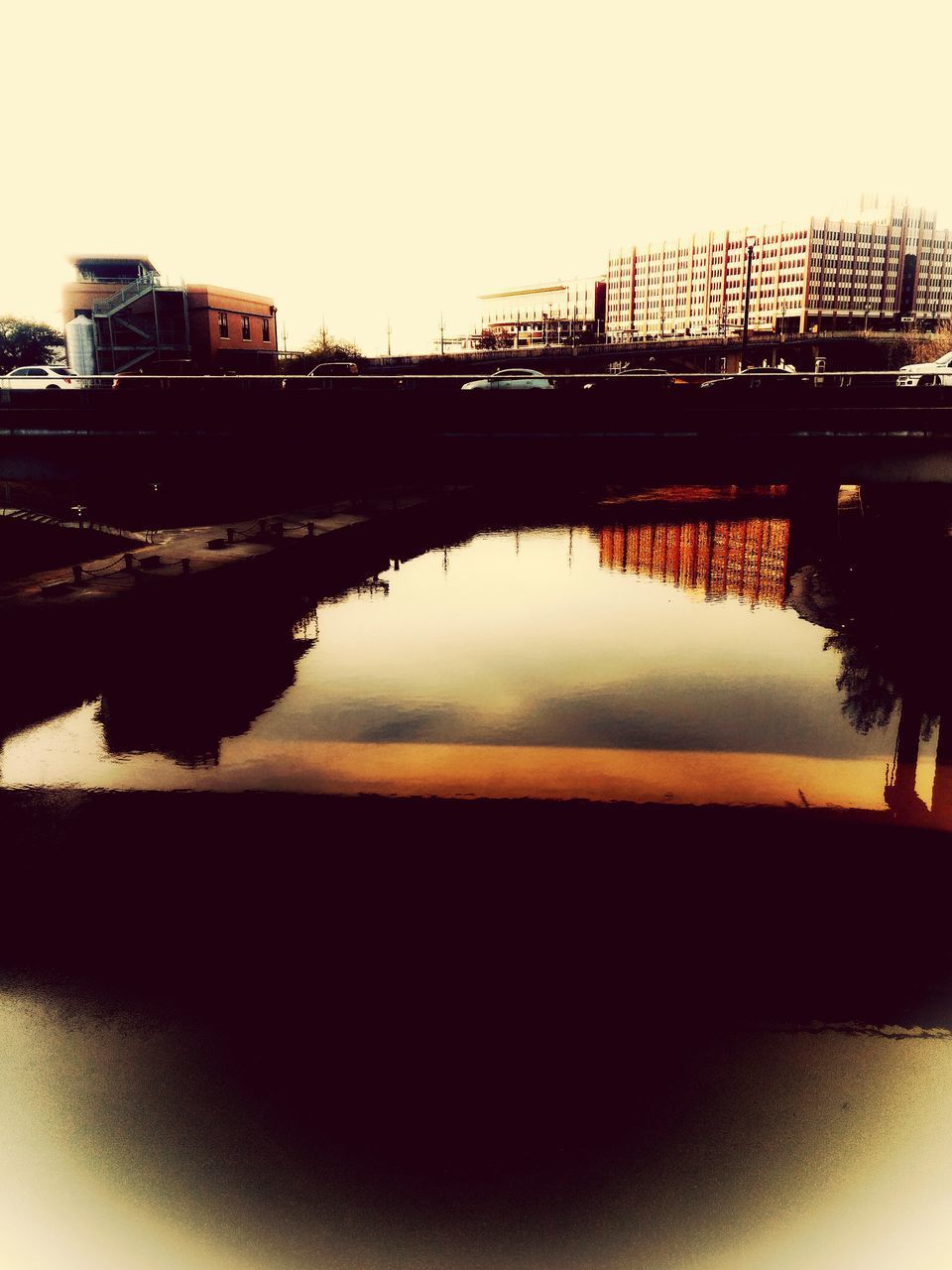 BRIDGE OVER RIVER BY BUILDINGS AGAINST SKY