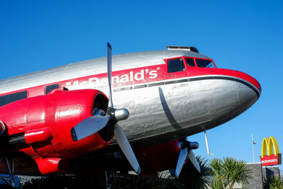 Low angle view of red airplane against clear blue sky