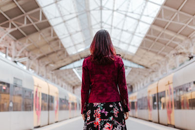 Rear view of woman standing at railroad station