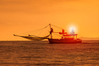 Fishing boat in sea against sky during sunset