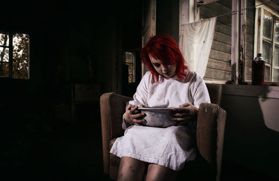 Depressed woman with bowl sitting on sofa at home