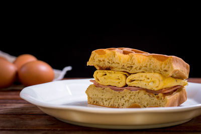 Close-up of bread in plate on table against black background