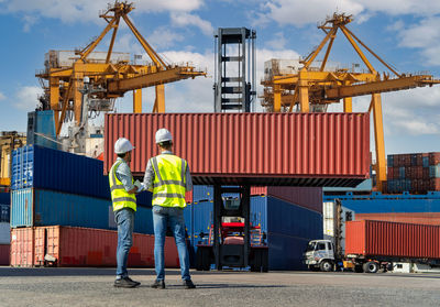 Engineers are overseeing the transportation of cargo with containers inside the warehouse.