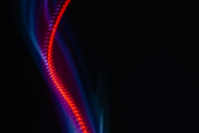 Close-up of illuminated light bulb against black background