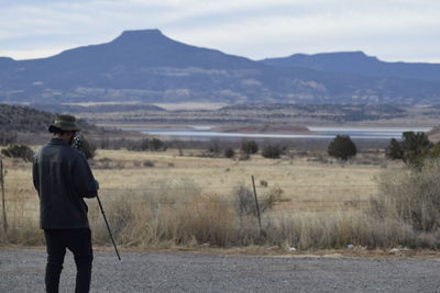 Rear view of man standing on road against mountains