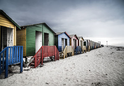 Row of hooded chairs on beach against sky