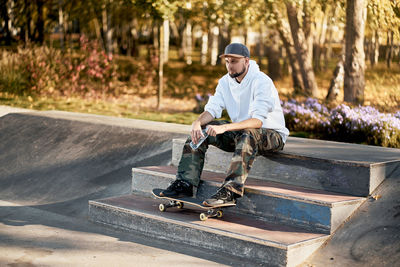 Full length of man with skateboard sitting on steps