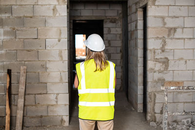 Rear view of man standing against yellow wall