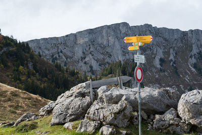 Close-up of road sign on rock against sky