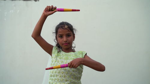 Indian beautiful little girl with garba sticks or dandiya on indian festival navratri.