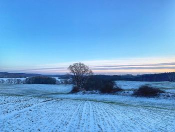 Snow covered field against clear blue sky