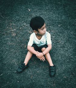 High angle view of boy sitting on field