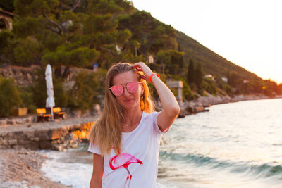 Portrait of woman standing at beach against sky