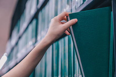 Close-up of hand holding umbrella against wall