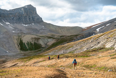 Rear view of people walking on mountain against sky