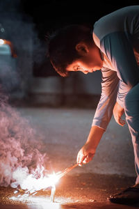 A malay boy igniting a fireworks during eid celebration in malaysia