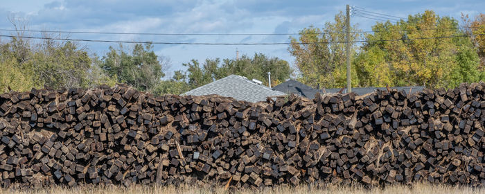 Stack of logs on field against sky