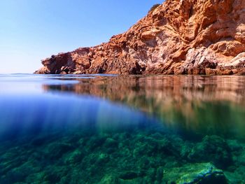 Rock formations by sea against sky